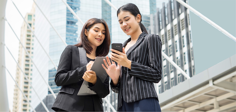 Two female business owners are looking at their phones and wondering, 