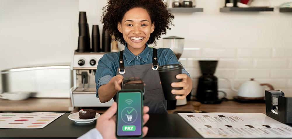 Customer pays for coffee with Stripe to a curly-haired female barista
